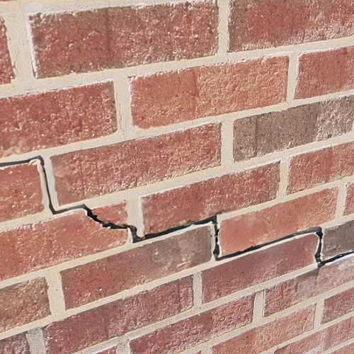 Brick wall with visible structural cracks running through the mortar